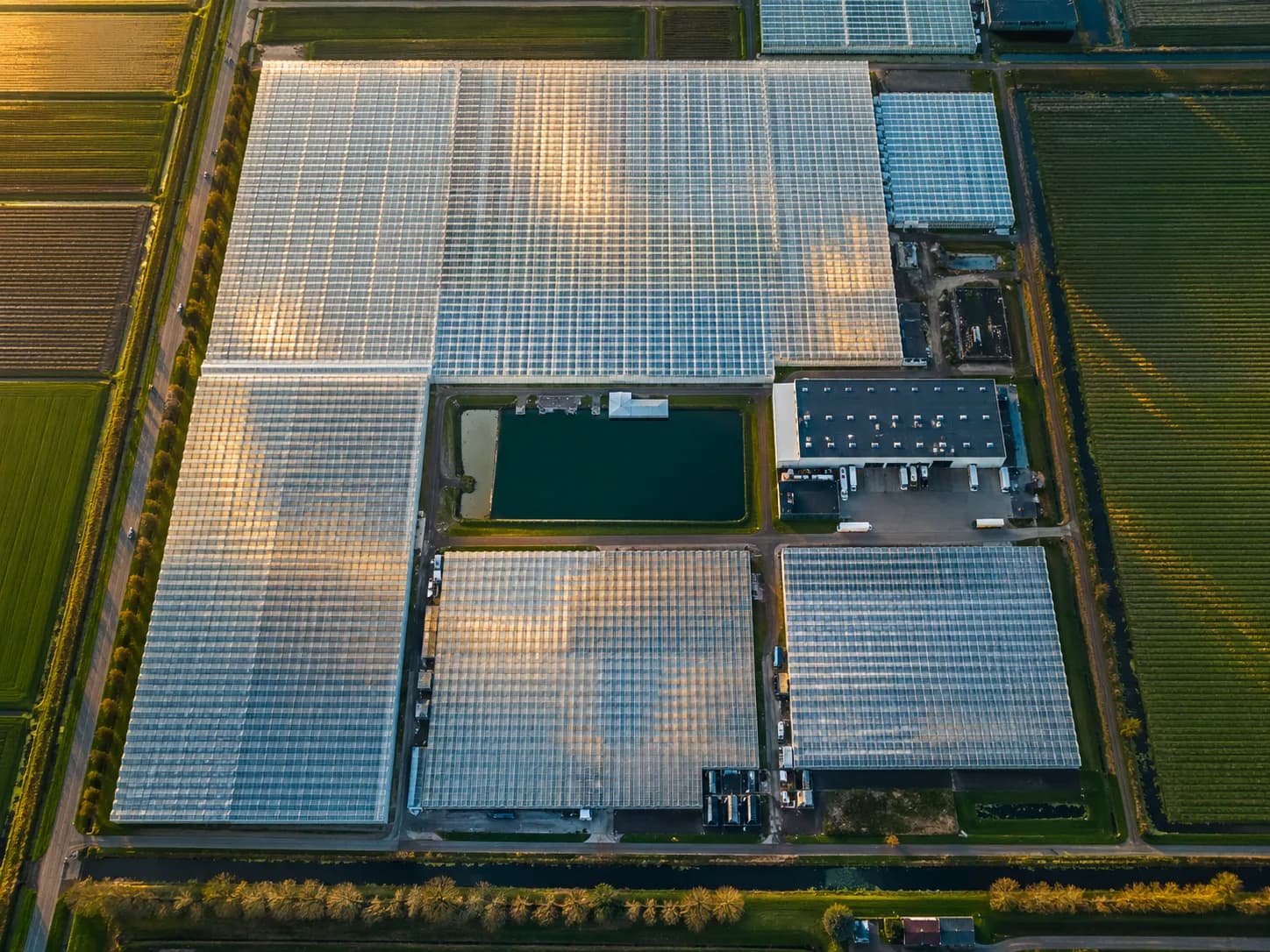 Luchtfoto van een glastuinbouwcomplex met waterbassin en kasoppervlak